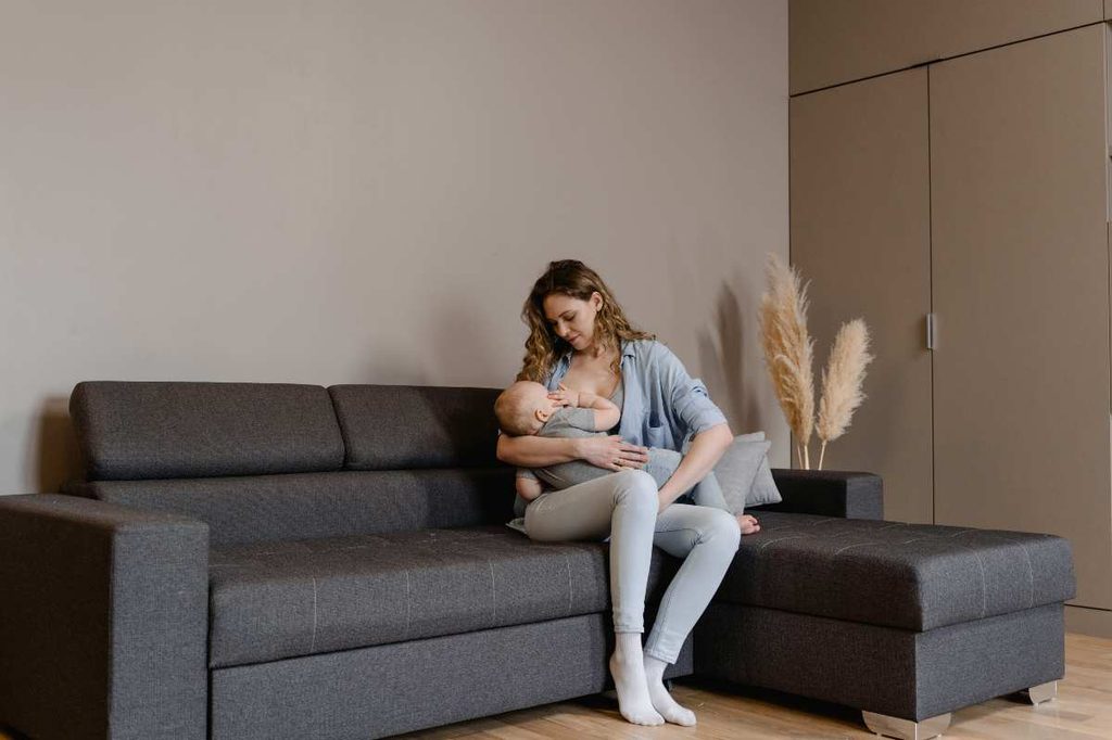 a woman breastfeeding on a leather sectional