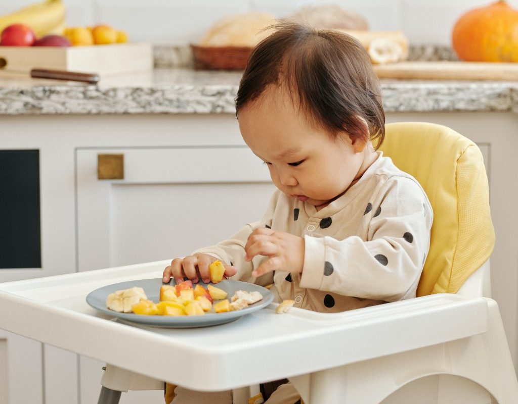 Baby eating solids in a high chair
