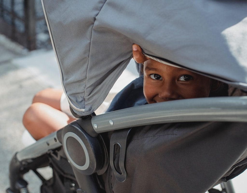 Child peeking out from the canopy of a stroller