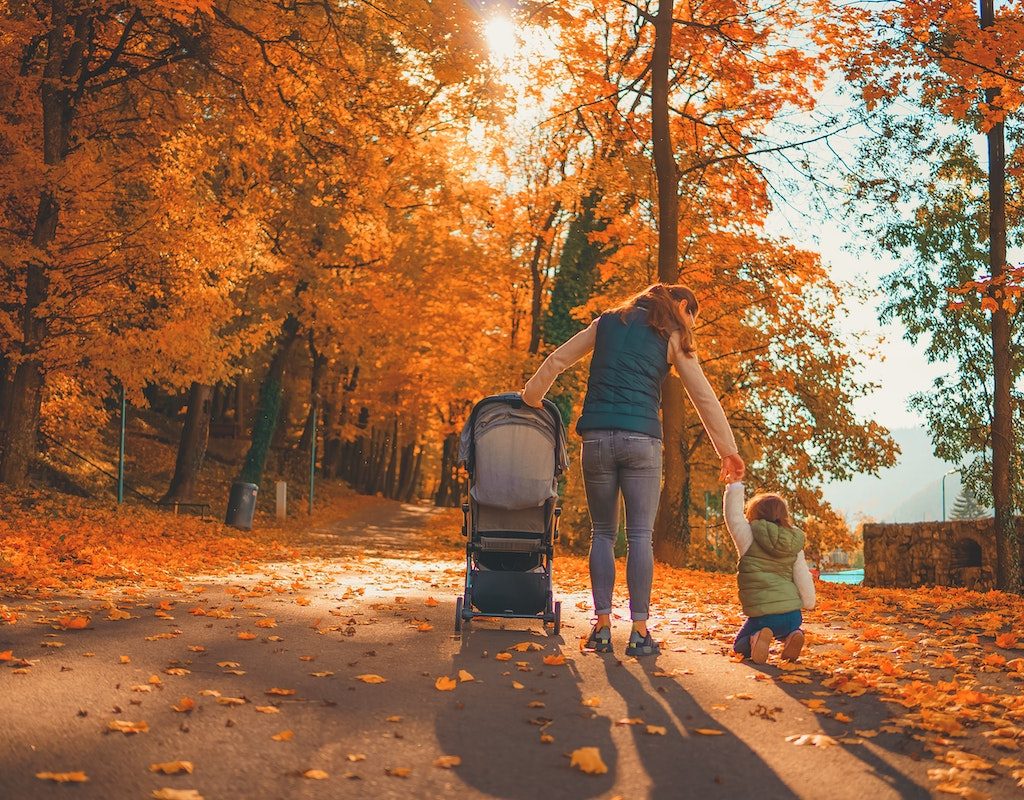 Mom pushing stroller with one hand while holding child's hand