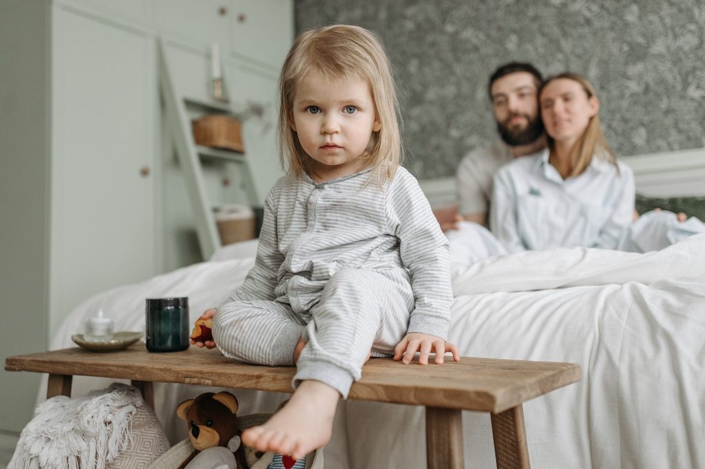 Small child sitting on the edge of a bed