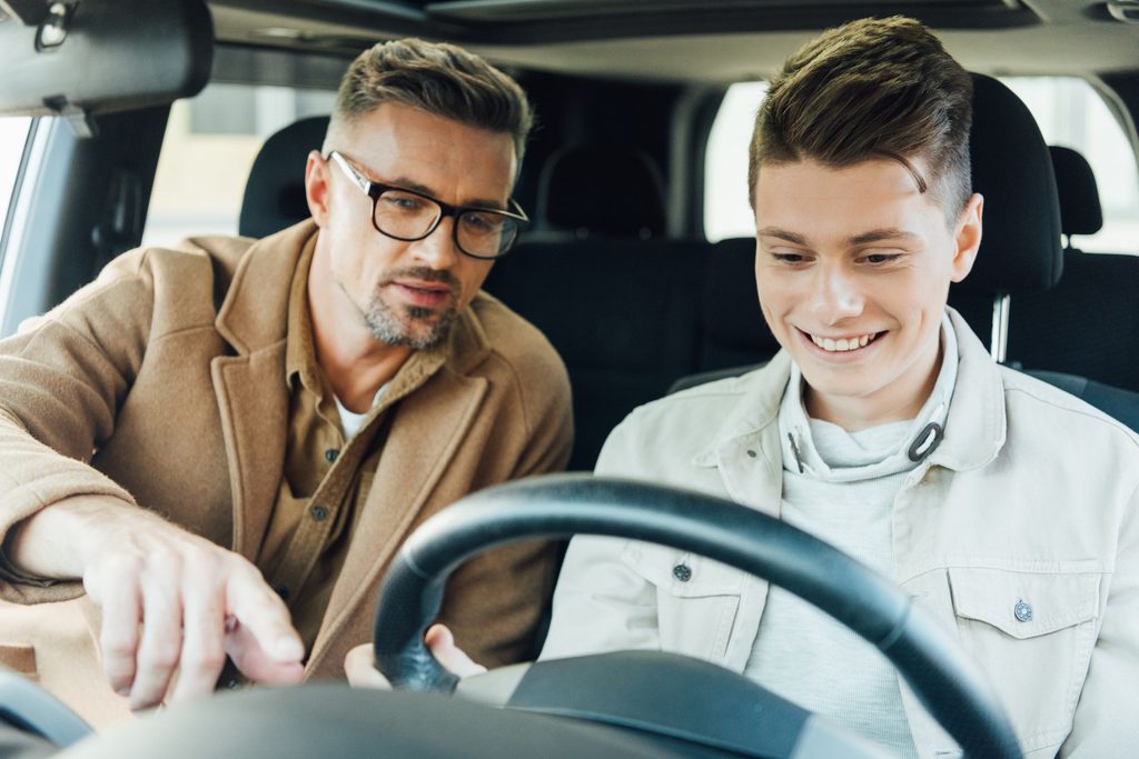 Teen boy driving with Dad