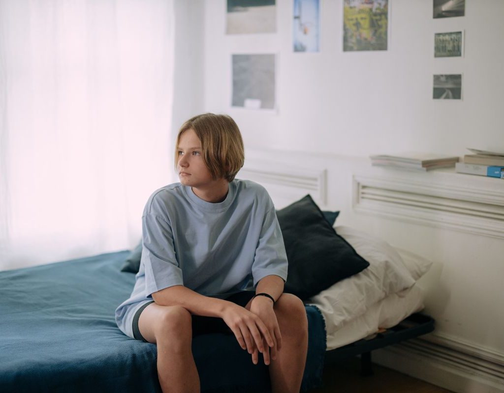Teen boy sitting on a bed