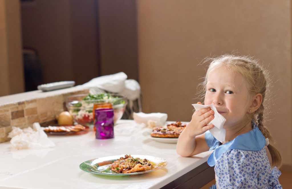 Young girl politely using a napkin at the table