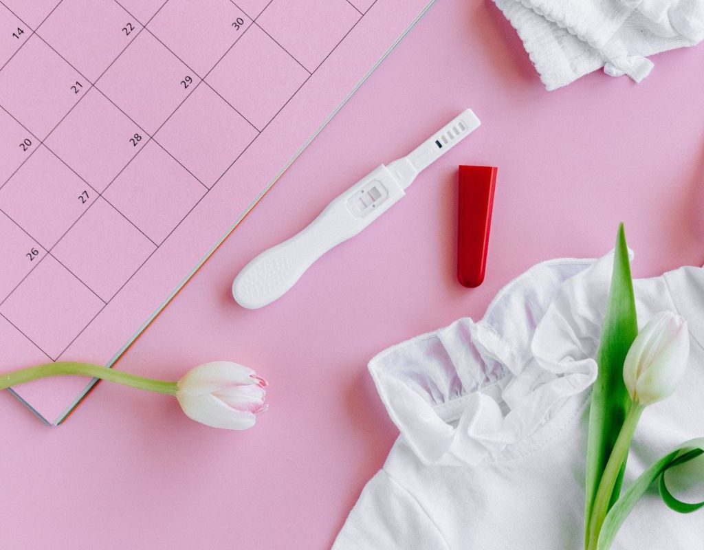 A pregnancy test with flowers and a calendar