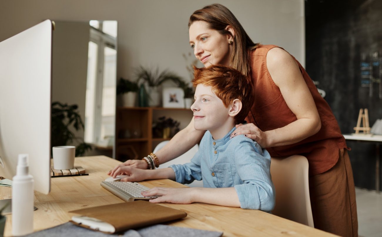 A mother helping her child with work on the computer.