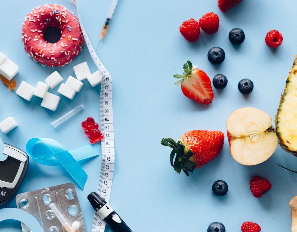 Produce, sugar, and diabetes monitoring equipment on a blue overlay