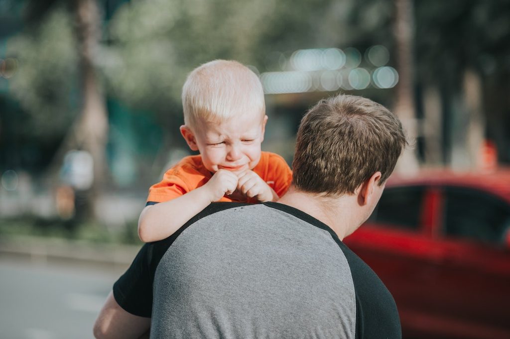 A dad holding a child who is crying