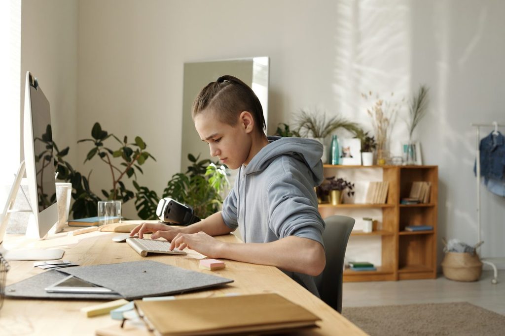 A child sitting at the desk typing away.