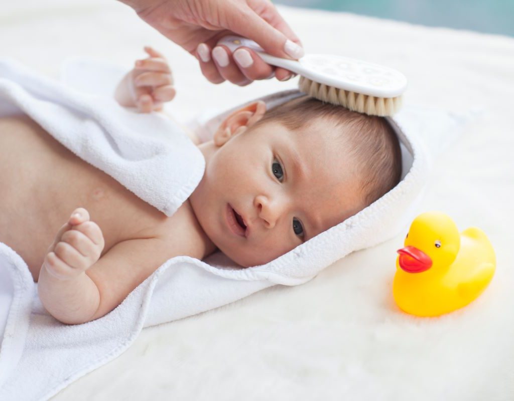 Parent brushing a baby's hair