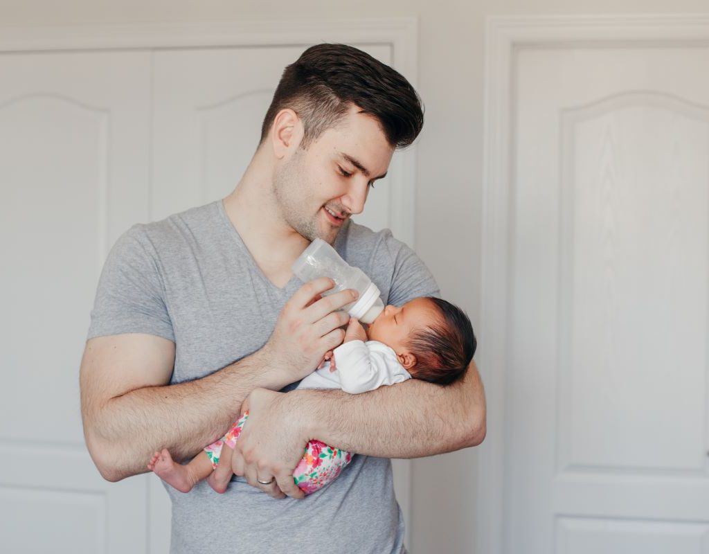 Dad feeding his newborn with a bottle.