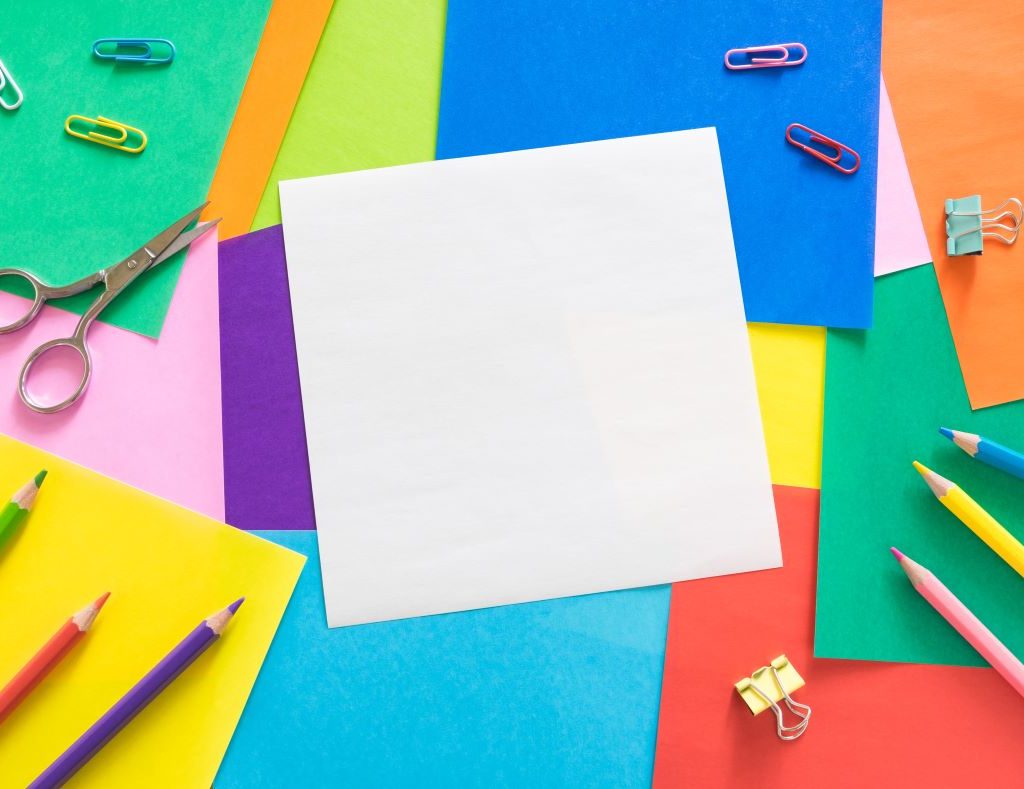 Colorful construction paper with pencils and paperclips