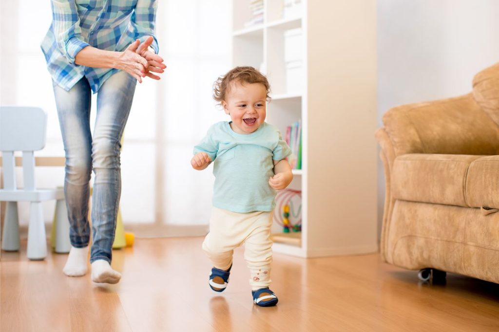 Happy toddler boy running with mom following behind.