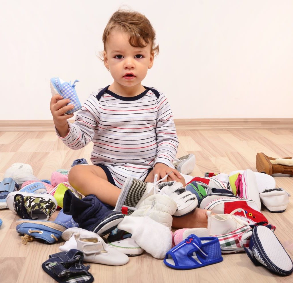 Baby sitting in a pile of baby shoes