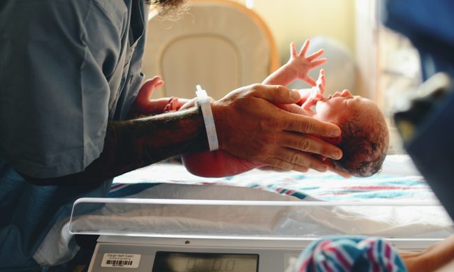 A parent holding a newborn baby in the hospital room