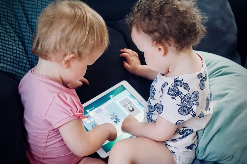 Two babies looking at the same screen.