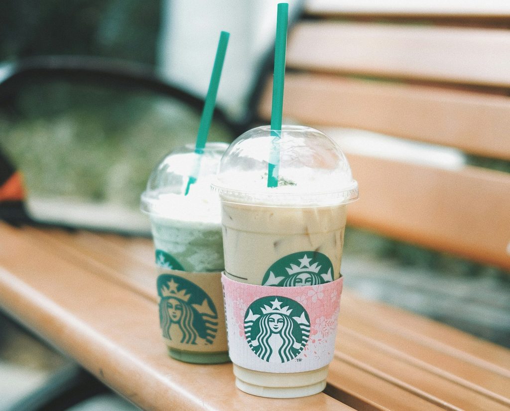 Starbucks drinks sitting on a bench.