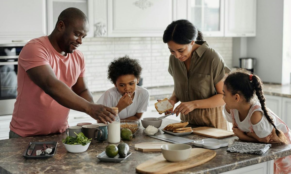 Parents and kids having fun in the kitchen making breakfast