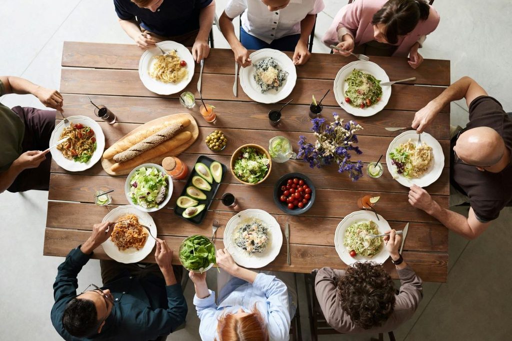 People gathered around table for Thanksgiving potluck dinner