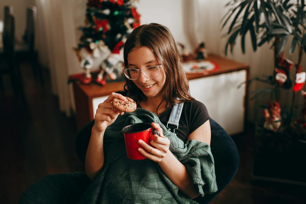 A child drinking hot cocoa and dunking a cookie.
