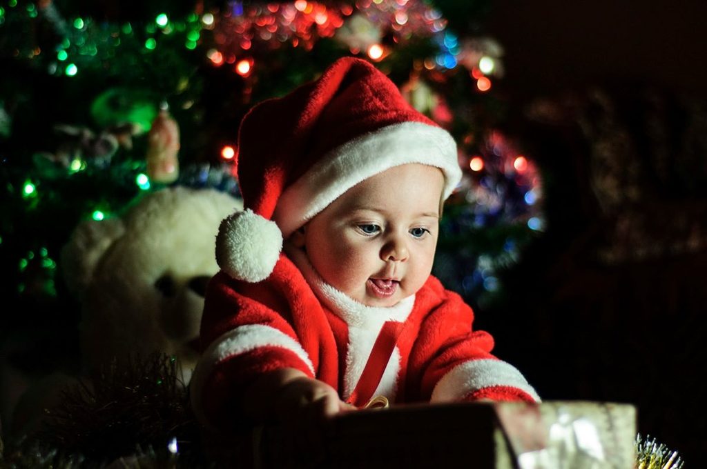 Baby dressed in a Santa suit under the tree