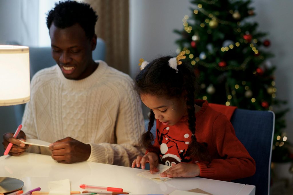 A father and daughter making Christmas crafts.