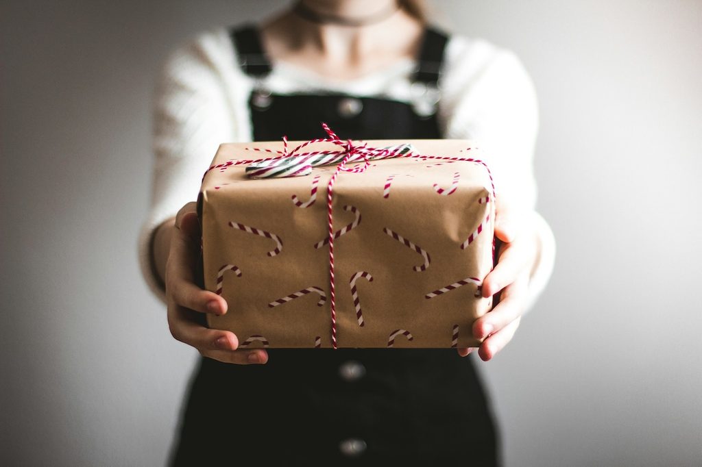 a person holding out a gift wrapped in brown paper with candy canes