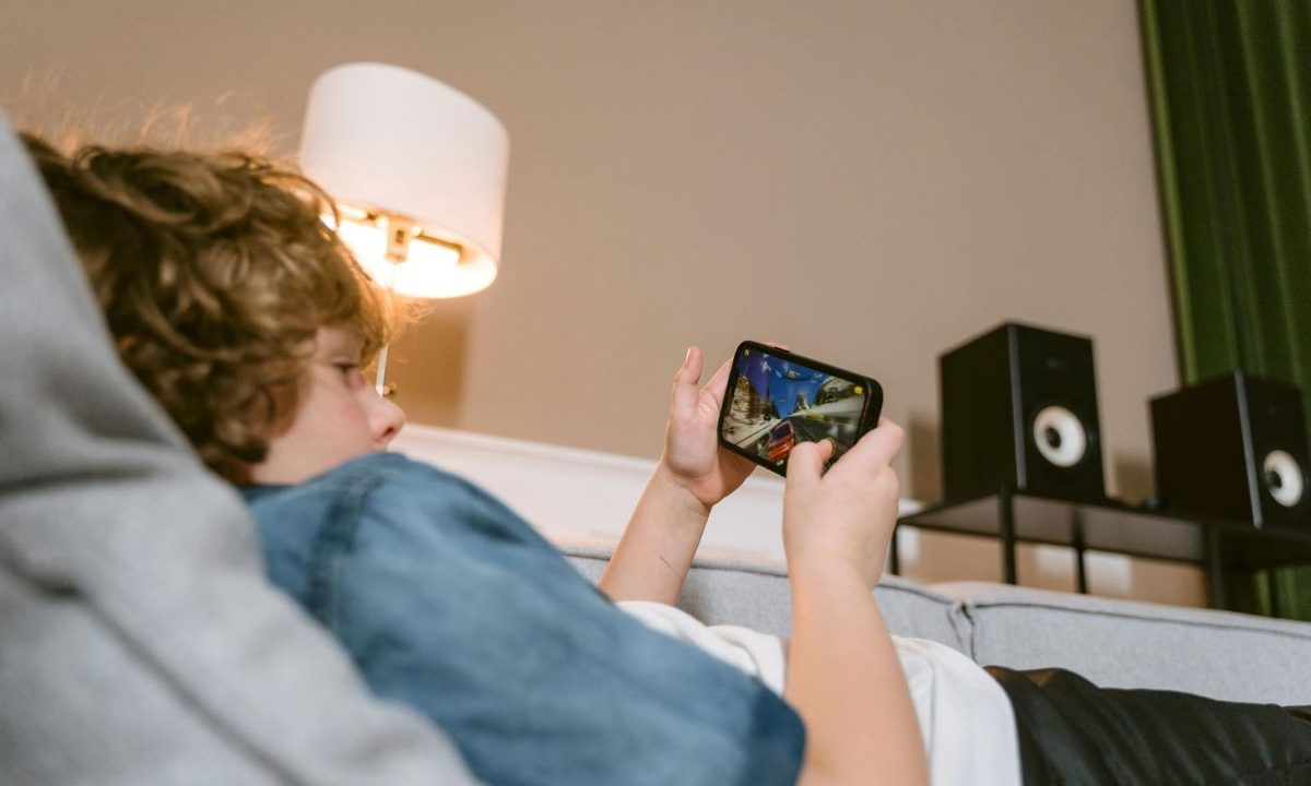 tween boy laying on couch on his cell phone