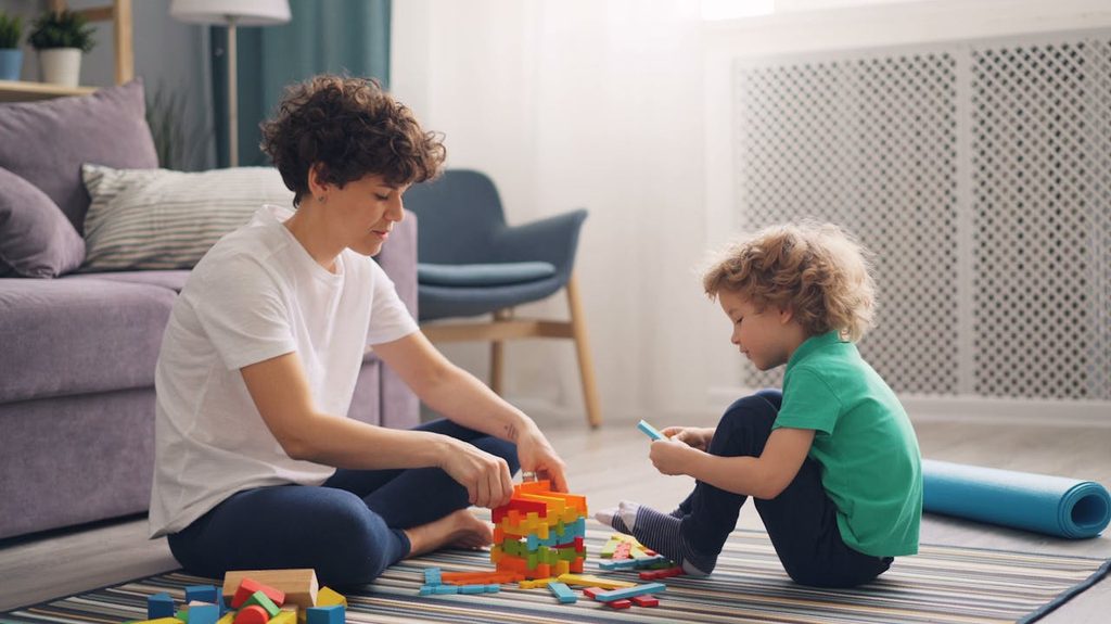 A caretaker playing with the child in the living room.