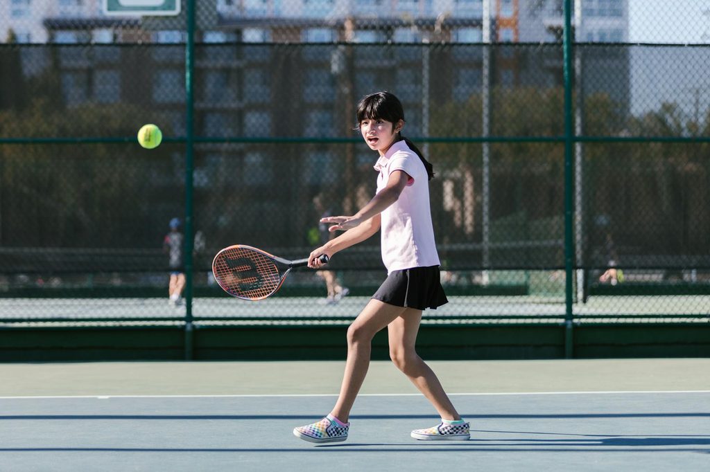 A child playing tennis outside.