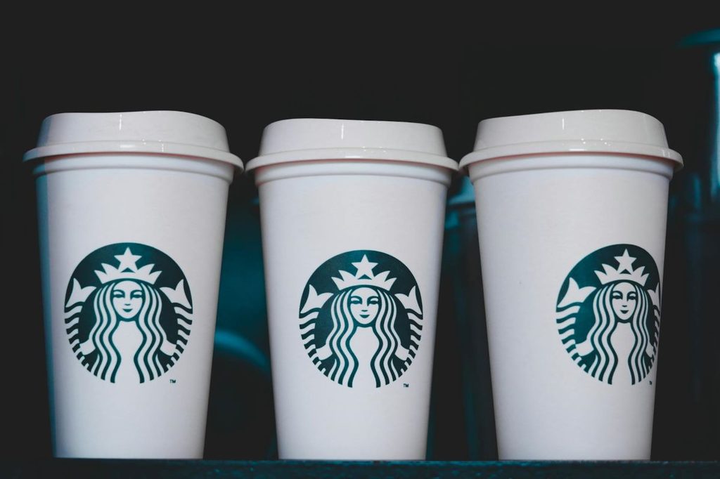 Starbucks cups lined up on a shelf