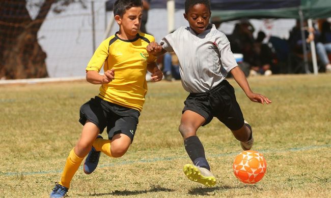 Two boys going after a soccer ball in a game