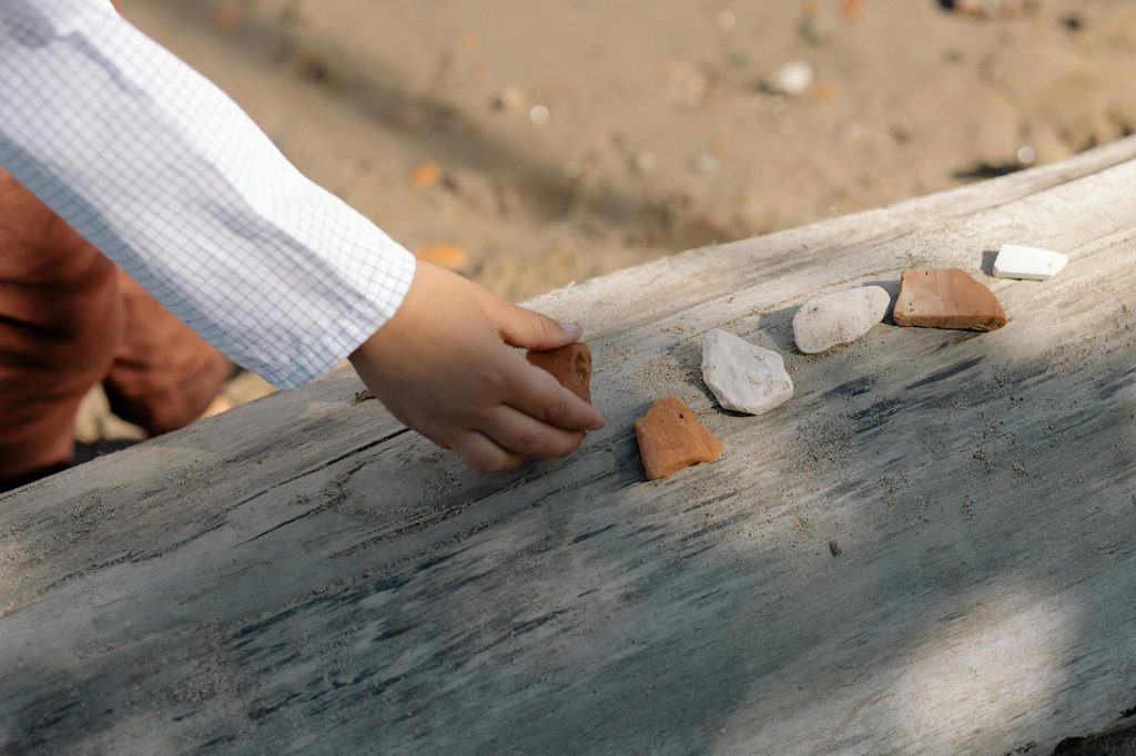 A child lining up rocks outside.