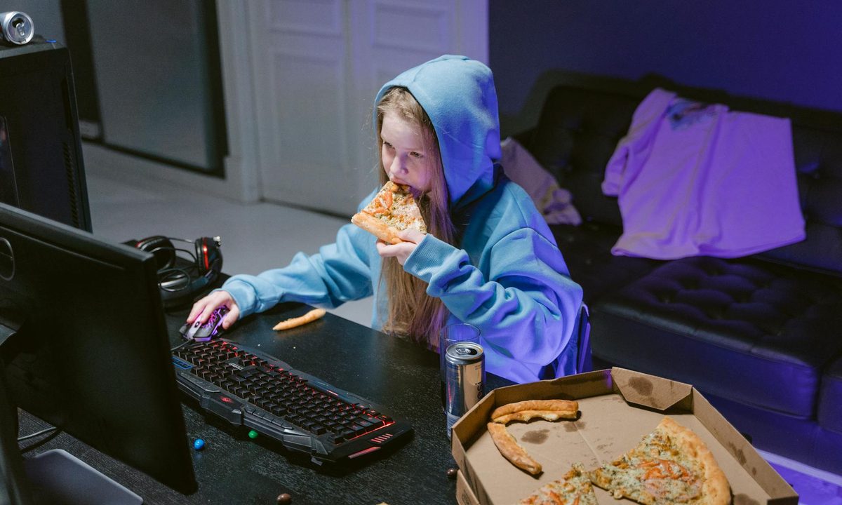 teen girl playing video games and eating pizza