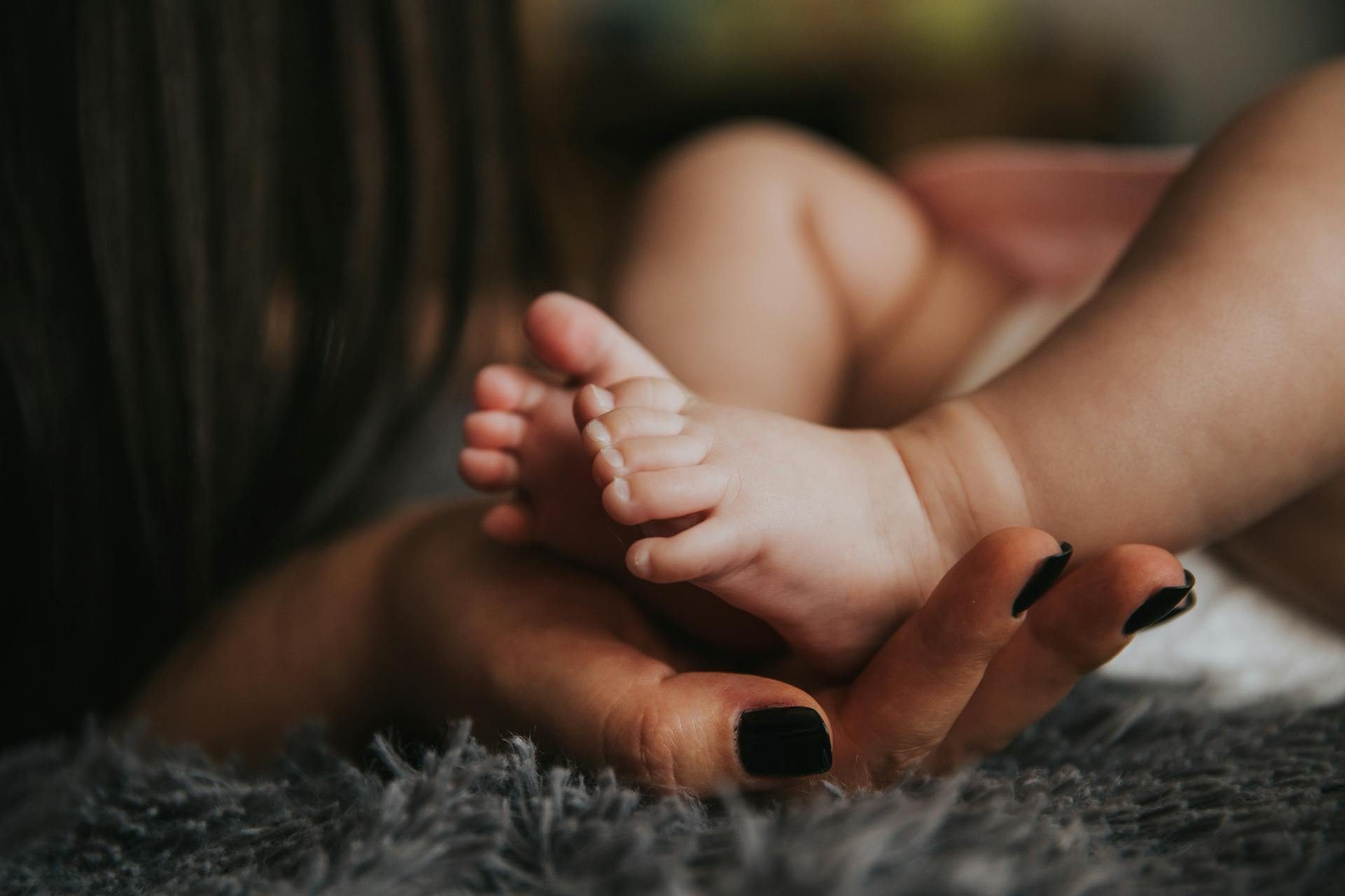 a mother holding a newborn baby's feet