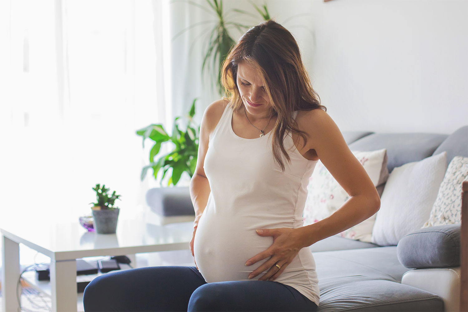 Pregnant woman on couch holding her stomach