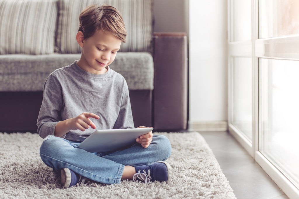 Boy sitting on a floor using a tablet
