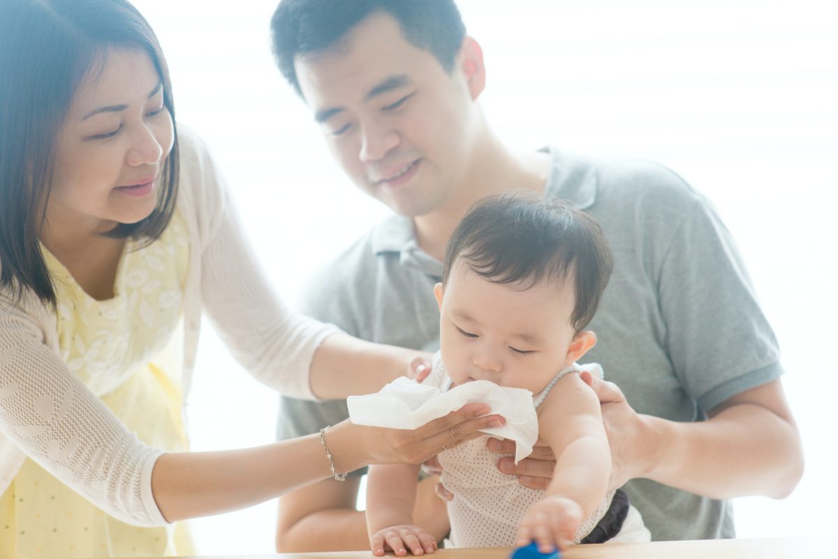 Parents cleaning a baby's face.