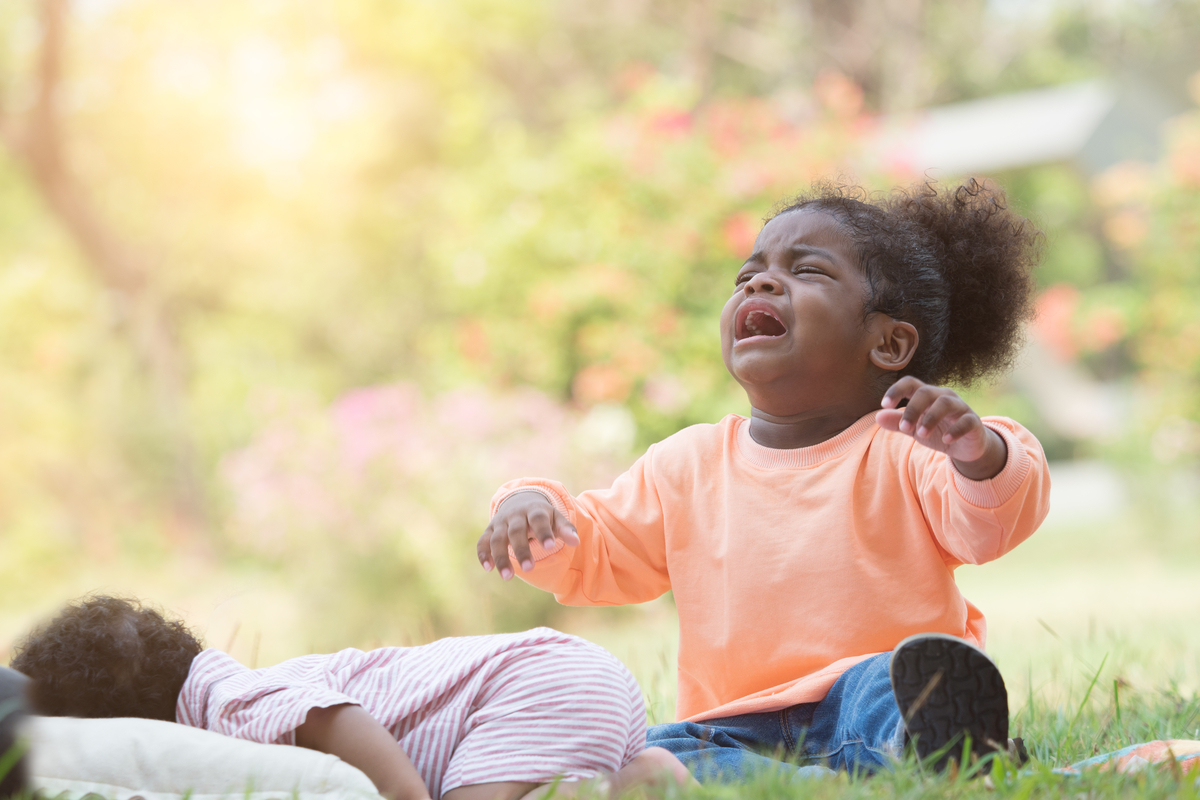 A toddler throwing a tantrum outside.