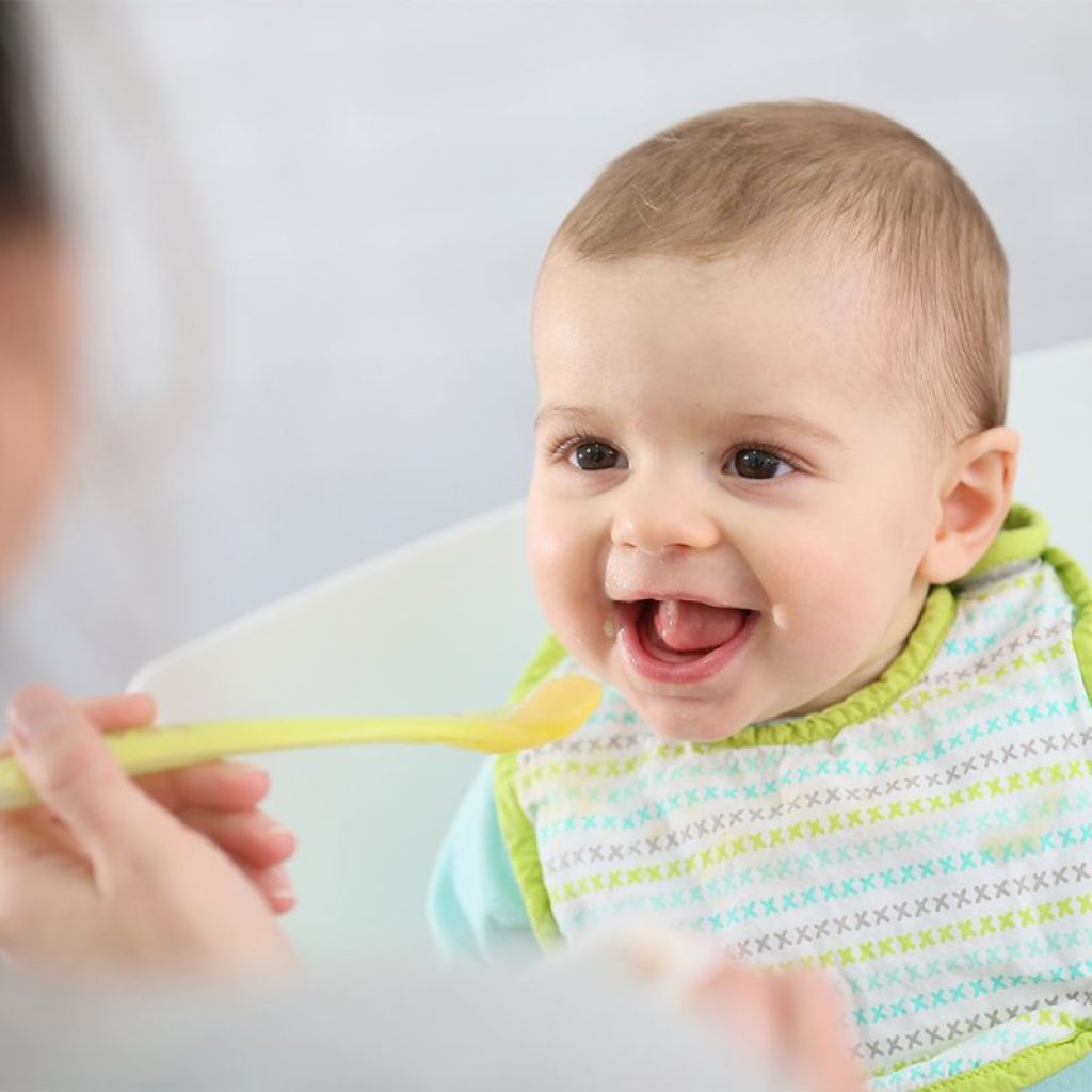 A parent feeding a baby some baby food