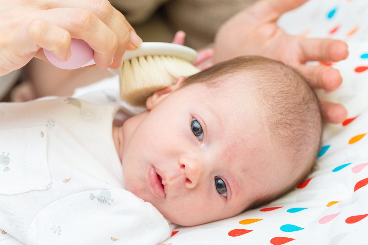 A parent brushing a baby's hair