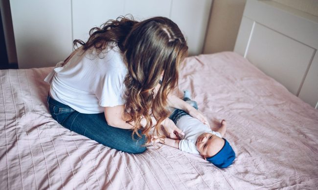 A mother changing a baby on a bed