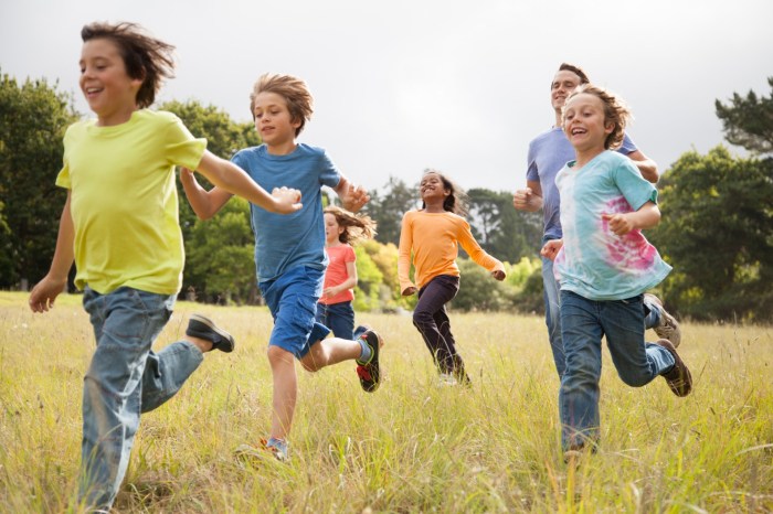 Group of kids running in a park with a dad