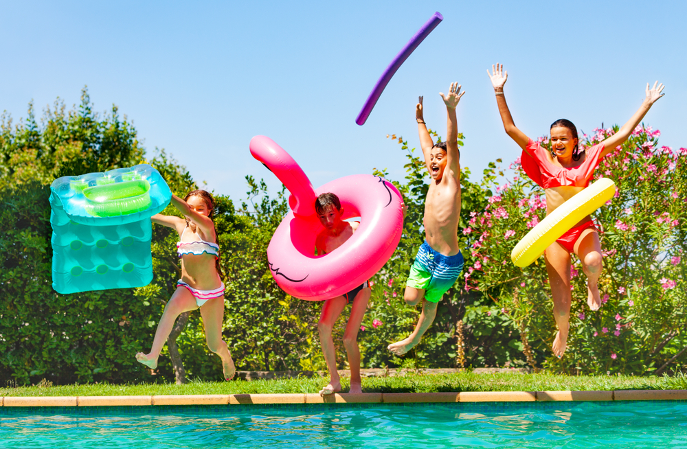 Kids jumping in pool using pool floats.