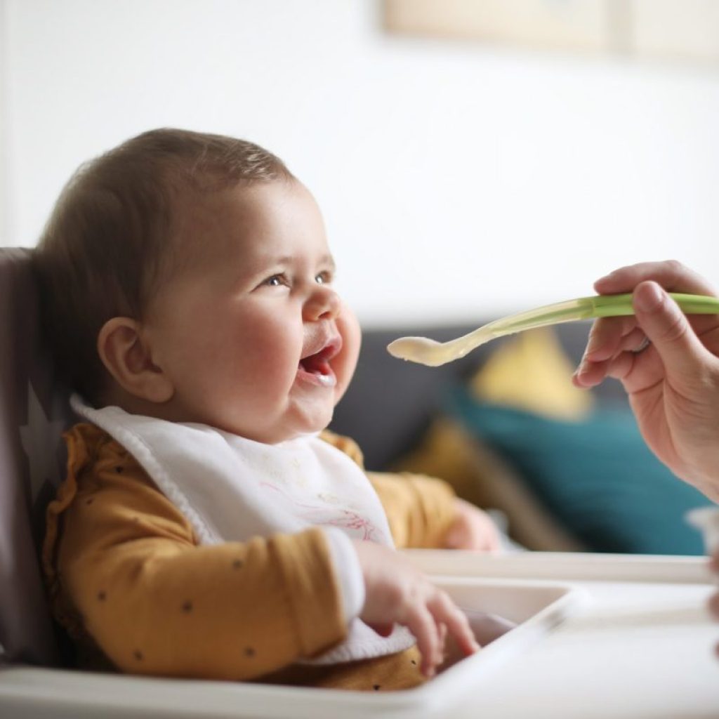 Baby in a highchair at the table eating.