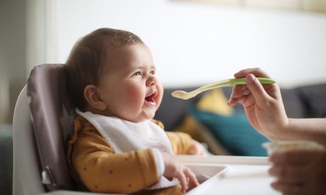 Baby in a highchair at the table eating.