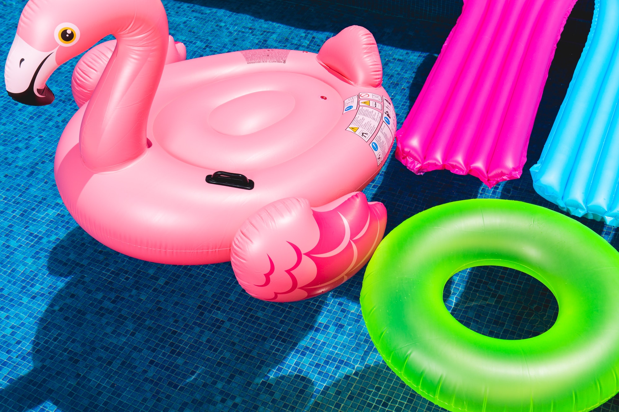 Four floating pool toys in a pool.