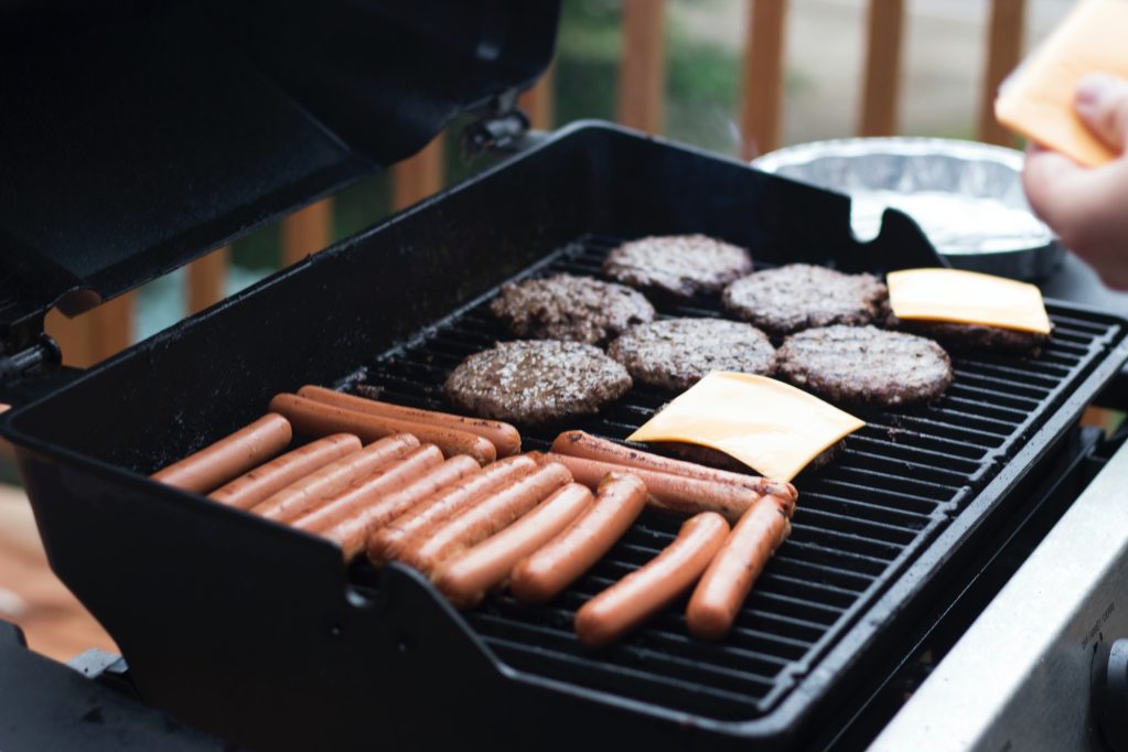 Hot dogs and hamburgers grilling for a budget-friendly birthday party meal
