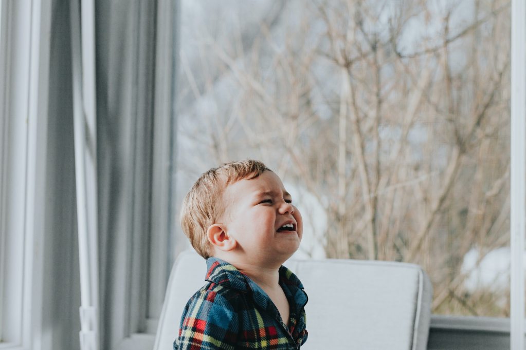 Child crying in a house by a window.