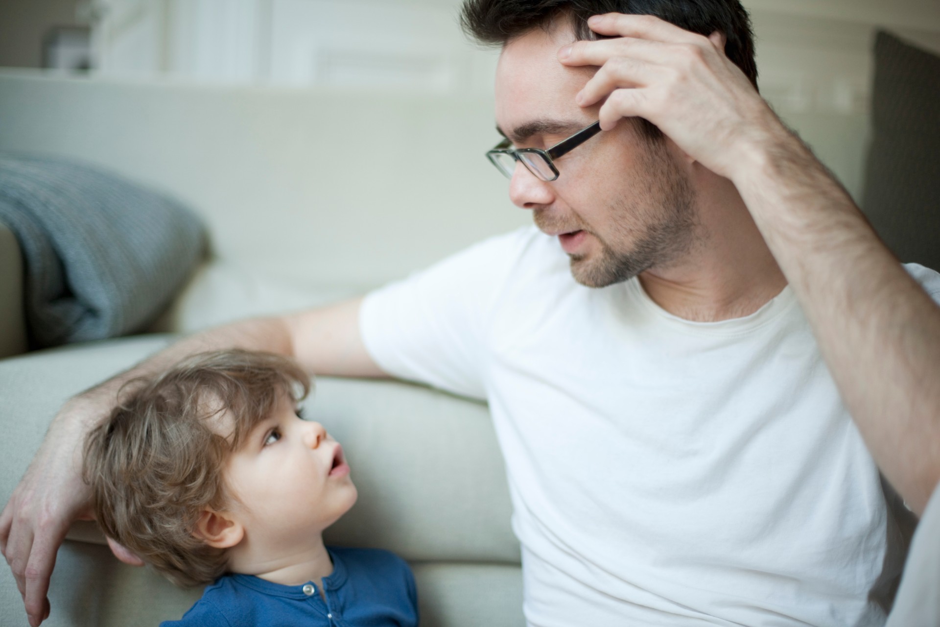Father talking with son on couch.